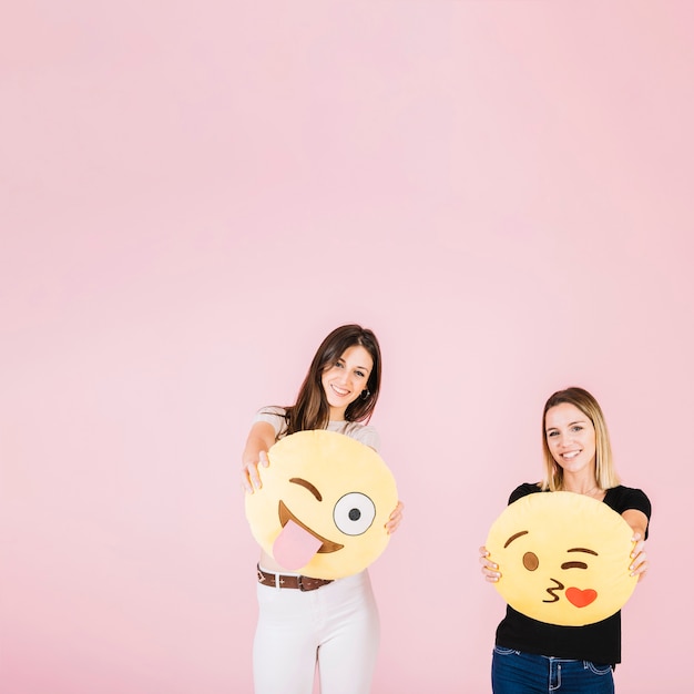 Free photo two happy woman with different emoji icons on pink background