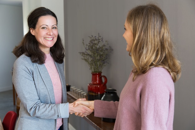 Two happy women standing and shaking hands