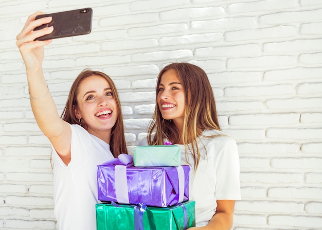 Two happy young women taking selfie on smartphone