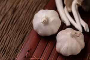 Free photo two heads of garlic on wooden slats and a fairy mushroom