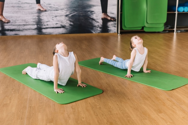 Two healthy girl exercising on green mat over wooden desk