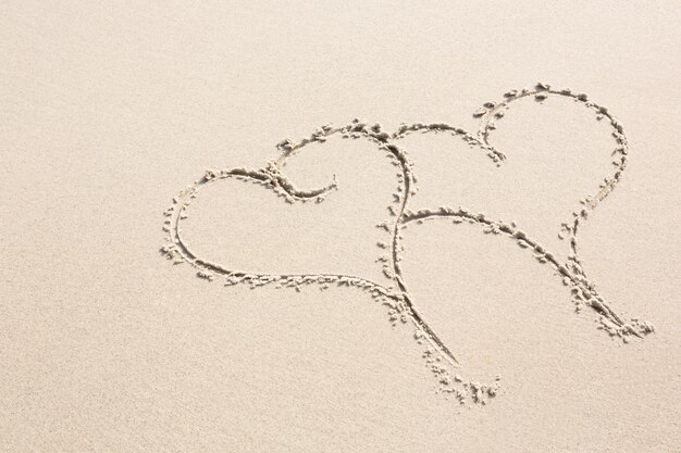 Two heart shapes drawn on sand