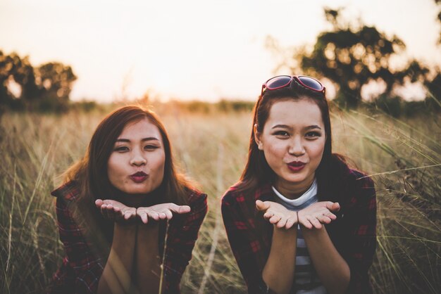 Two hipster teenage girlfriends having fun in field. Women lifestyle concept.