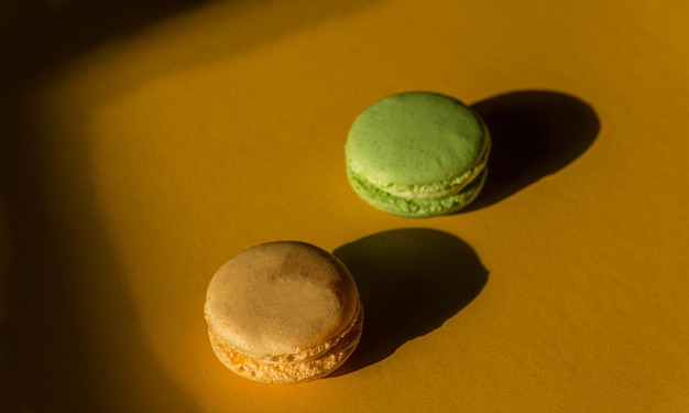 Two isolated macarons yellow and green on a yellow ground showing their shades