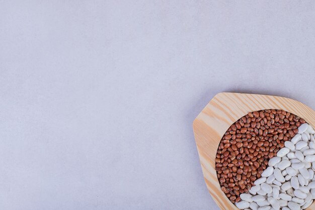 Two kinds of raw beans and peas in wooden plate.