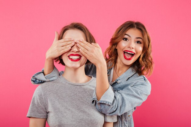 Two ladies friends covering eyes with hands.