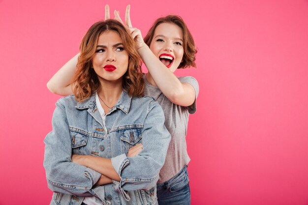 Two ladies friends standing isolated have fun.