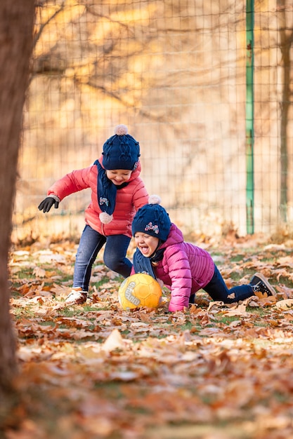 The two little baby girls playing in autumn leaves