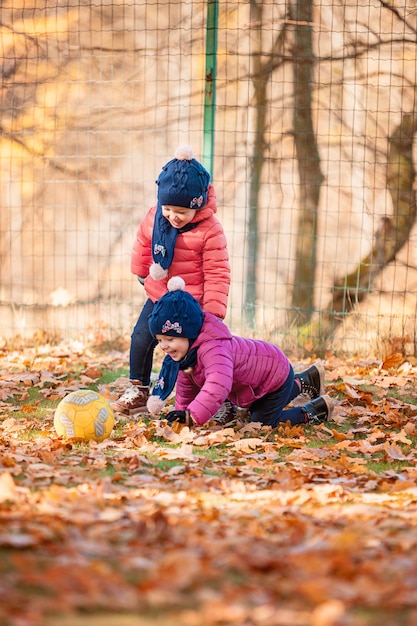 two little baby girls playing in autumn leaves