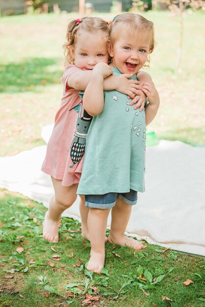 The two little baby girsl playing against green grass in park