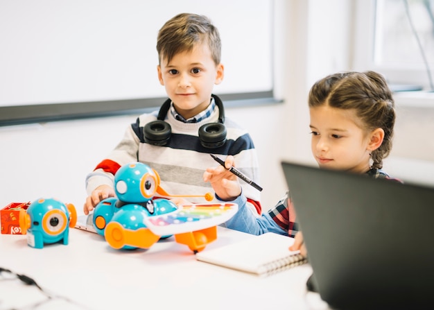 Two little children playing with digital toys in the classroom