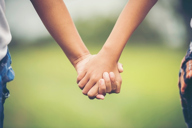 Two little girl friendship hand holding together in the park