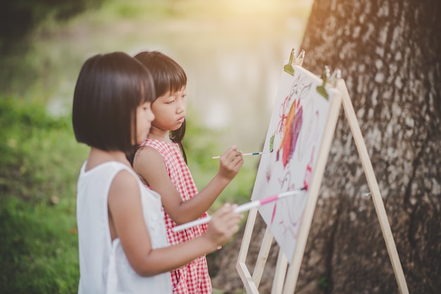 Two little girl painter art drawing in the park