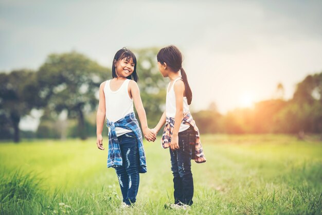 Two little girls hand holding together having fun in the park