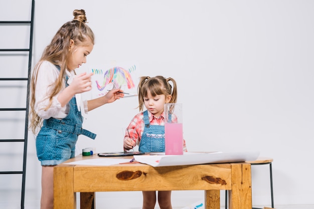 Two little girls painting with aquarelle on paper