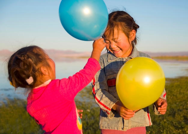 Free photo two little girls playing with each other with balloons.