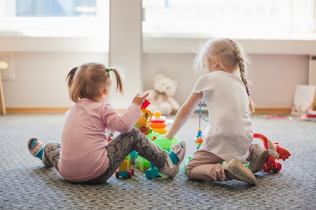 Two little girls sitting on floor playing