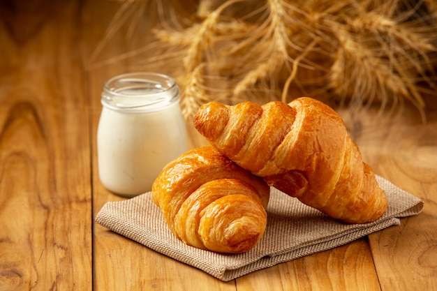 Two loaves of bread and milk put in a glass on the old wooden floor.