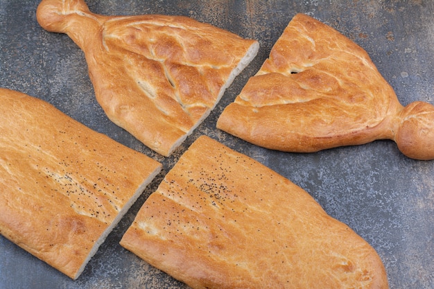 Two loaves of tandoori bread sliced in halves on marble surface