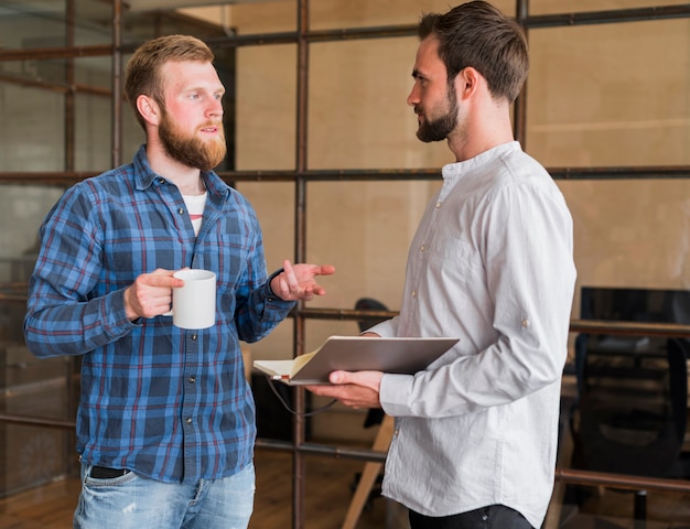 Free Photo two male colleague discussing with each other at workplace