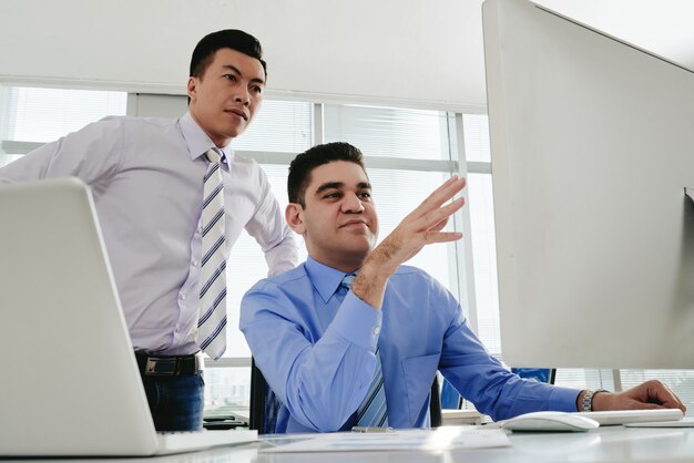 Two male coworkers collaborating on a project at the office computer