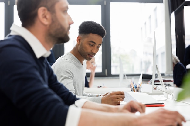 Two male coworkers working at computer in an office