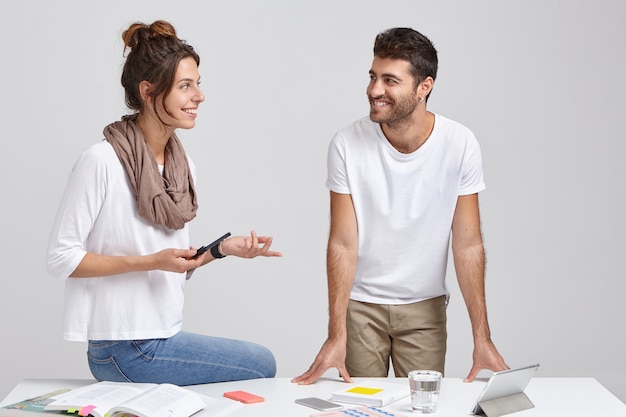 Free Photo two man and woman collegaues or partners have active discussion of future plans, look happily at each other