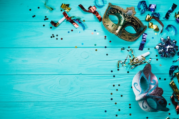 Two masquerade carnival mask with confetti over blue table