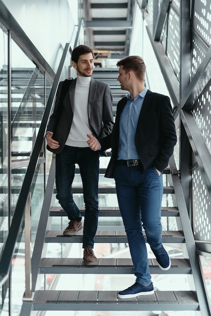 Two men going up, down stairs while chatting