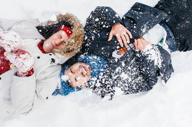 Free Photo two men lying covered with snow 