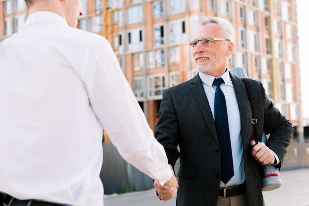 Free photo two men shaking hands outdoors