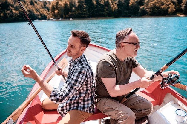 Free photo two men sitting and fishing in canoe