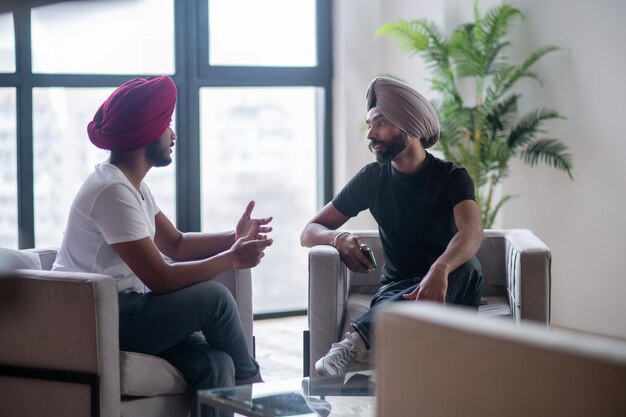 Two men in turbans talking and looking involved