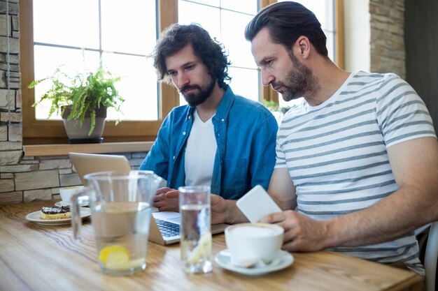 Two men using a laptop