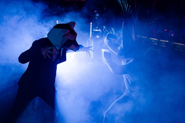 Two men with animal masks posing at the party in the club