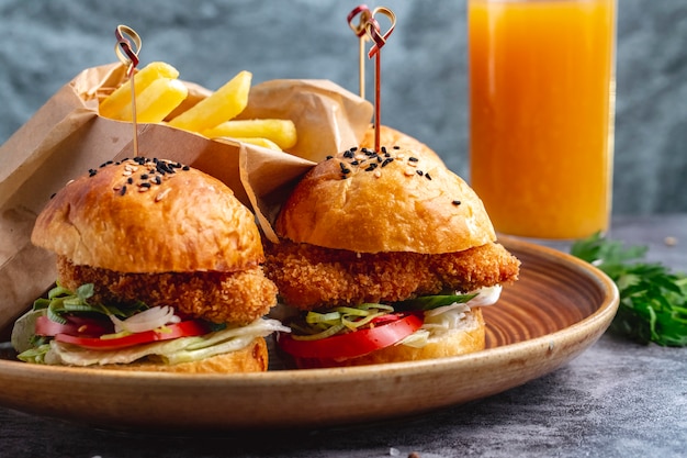 Two mini chicken nuggets burgers served with french fries in paper box