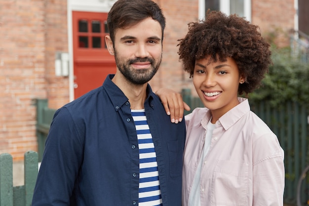 Free photo two mixed race girl and boy stand closely to each other, being in good mood, have stroll outdoor