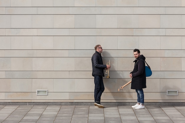 Free Photo two musicians standing in front of wall