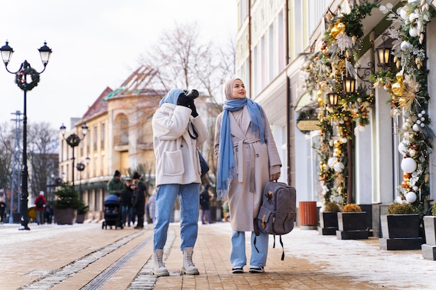 Two muslim female friends taking photos of the buildings while traveling