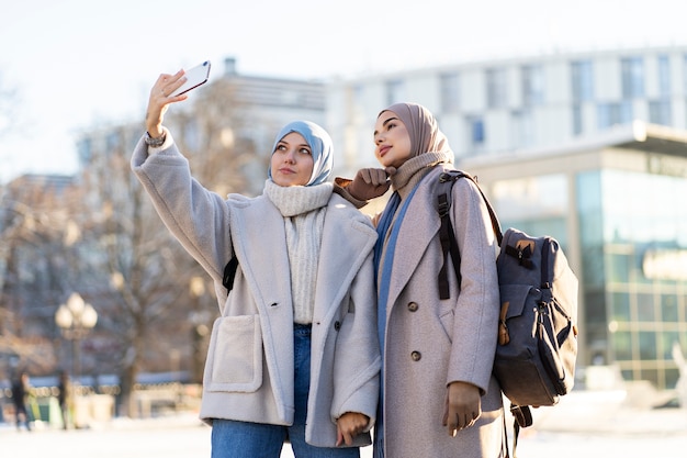 Two muslim female friends taking a selfie while traveling in the city