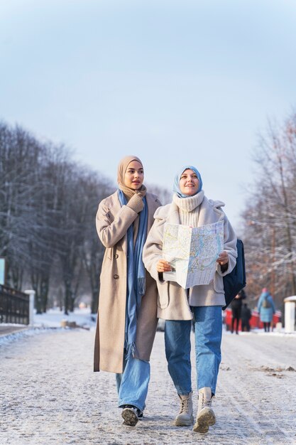 Two muslim women with hijabs consulting a map while traveling in the city