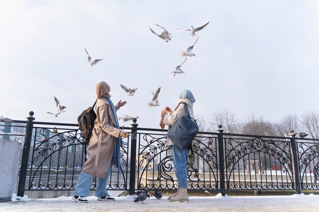 Two muslim women with hijabs looking at the pigeons while traveling