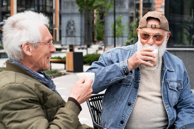 Free photo two older men in the city having coffee together and chatting