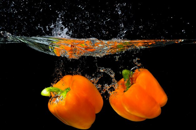 Two orange bell pepper floating under the water