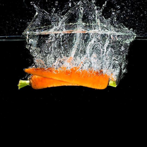 Free Photo two orange carrots falling into water splash