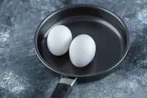 Free photo two organic chicken egg on black frying pan.