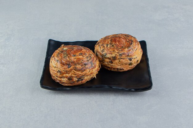 Two pastries with chocolate on dark plate. 