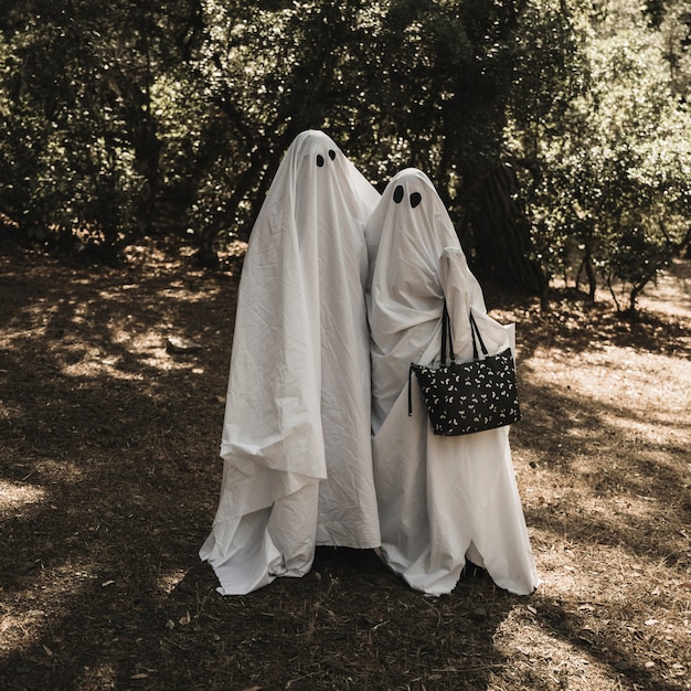 Free Photo two people in ghost costumes hugging each other in forest