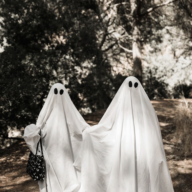 Two people in ghost costumes walking in forest