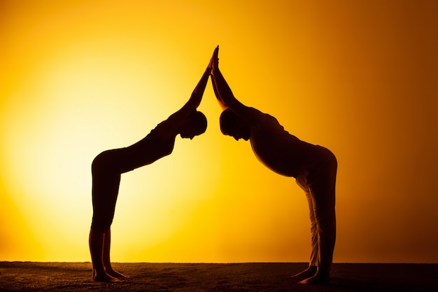 Free photo two people practicing yoga in the sunset light